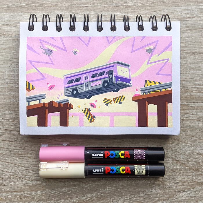 A vibrant James Chapman sketch of a purple bus leaping a broken bridge, with pink and yellow rays. Pink and black uni POSCA paint pens are placed below the sketchbook on a wooden surface, capturing the artist’s dynamic style.