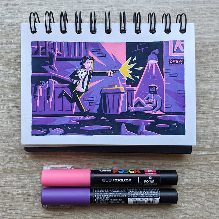 The James Chapman spiral sketchbook showcases a vibrant John Wick-inspired alley shooting scene, illustrated with pink and purple POSCA paint pens on paper, with both markers placed on the wooden surface below.
