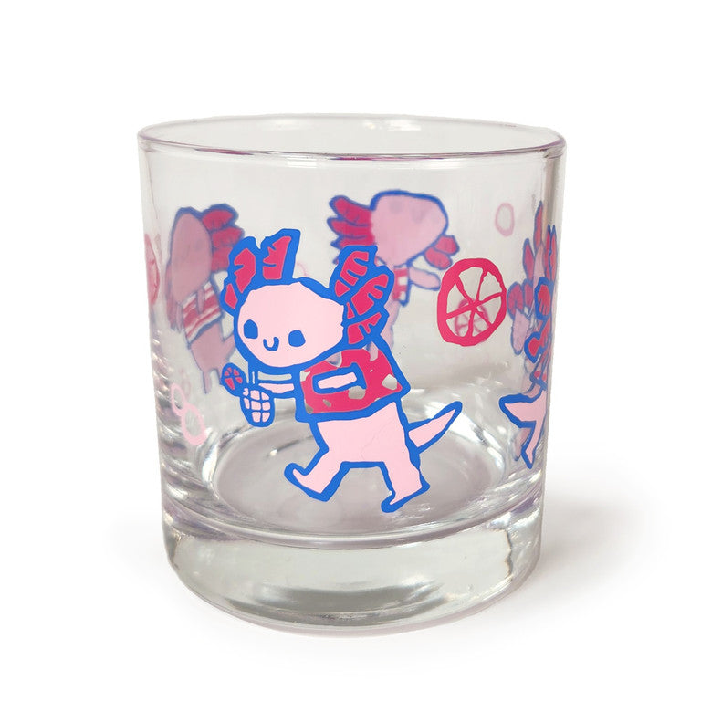 This Spoke Art clear glass tumbler showcases Scott C.s playful cartoon axolotls holding drinks and snacks, surrounded by charming bubbles and citrus slices.