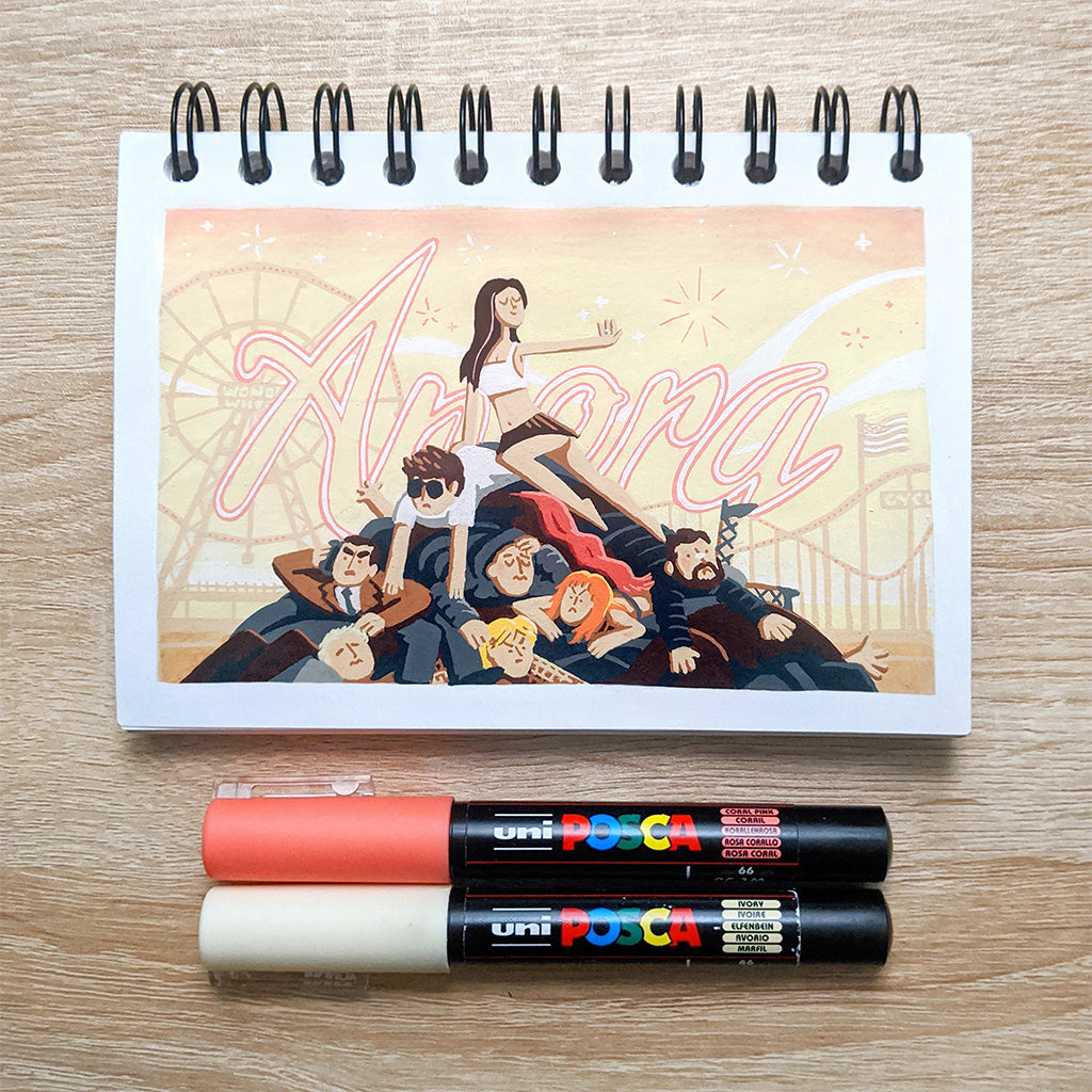 Discover the Anora 2024 sketchbook featuring a James Chapman illustration of people lounging under a triumphant woman. A roller coaster and Amaya are seen in the background, with two Posca markers, peach and black, below. Available at Spoke-Art.com.