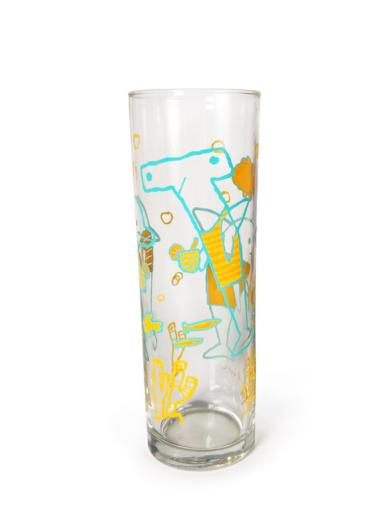 A clear glass by Scott C. with playful blue and yellow cartoon art, featuring a dinosaur in a vest with a bucket, plus small objects, plants, and ocean life details.