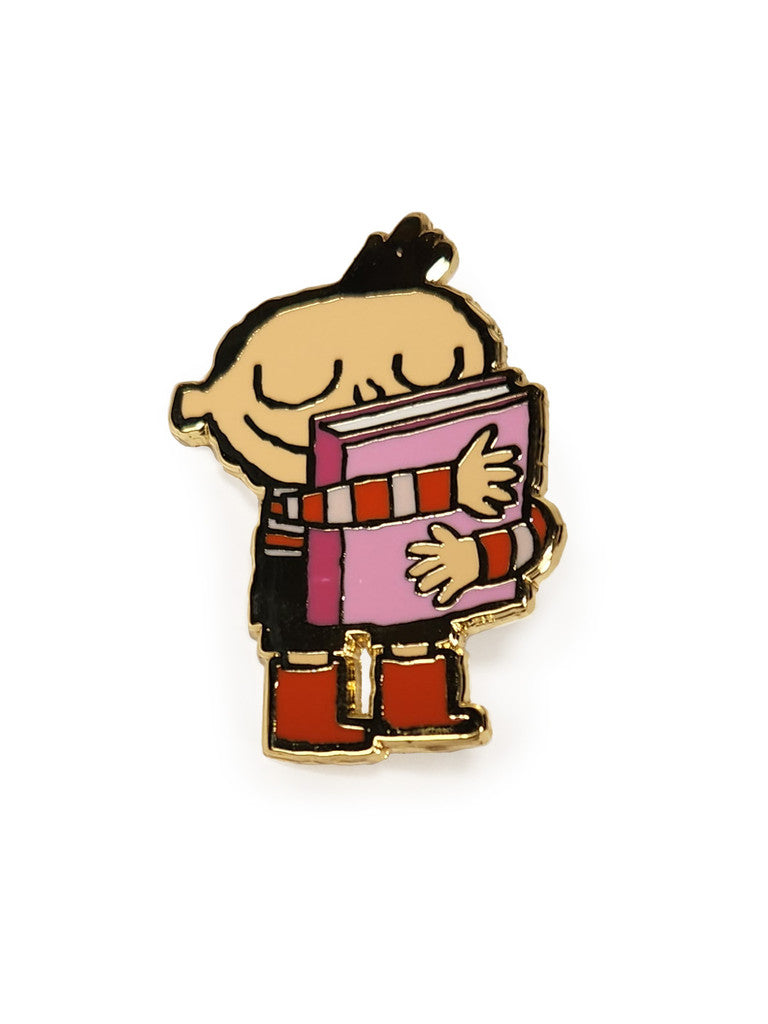 Scott C. limited edition hard enamel pin featuring a happy cartoon character with closed eyes, striped shirt, red boots, and hugging a large pink book. Gold metal plating on a white background.