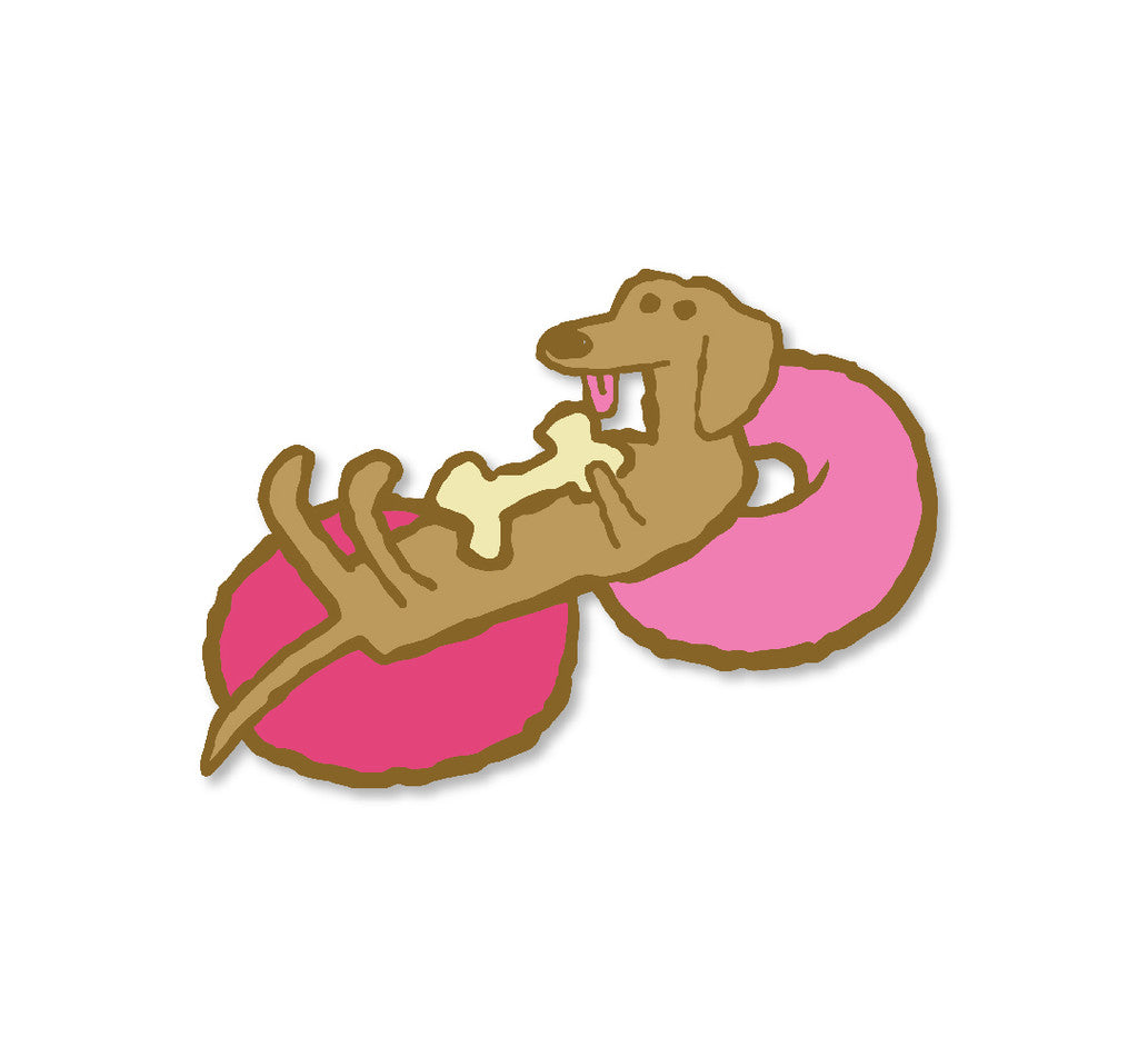 A cartoon brown dachshund lies on its back atop a pink frosted donut, holding a bone and smiling with its tongue out. This Scott C. hard enamel pin shines with gold metal plated details—perfect for collectors!.