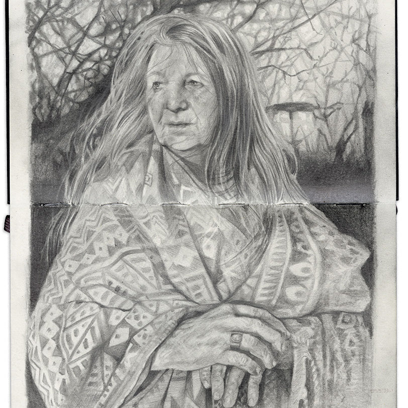 illustration in an open face Moleskine notebook of an older woman in a patterned blanket with long hair standing in front of a tree by artist Roos van der Vliet