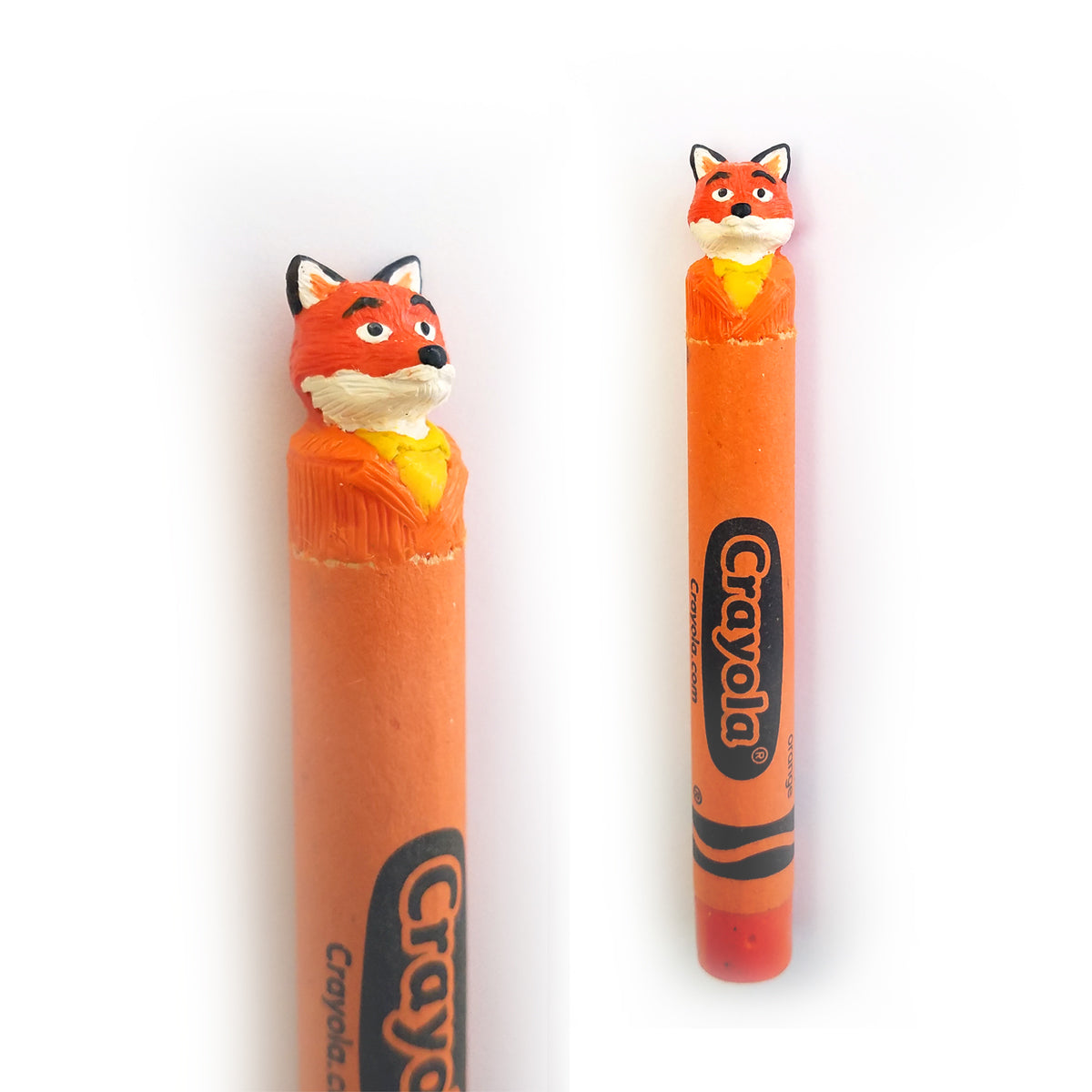 The Hoang Tran hand-carved orange crayon, named Waxstick Mr. Fox, showcases a detailed fox head adorned with a yellow scarf. It stands upright, featuring an intricate carving and the iconic Crayola label as a nod to Fantastic Mr. Fox.