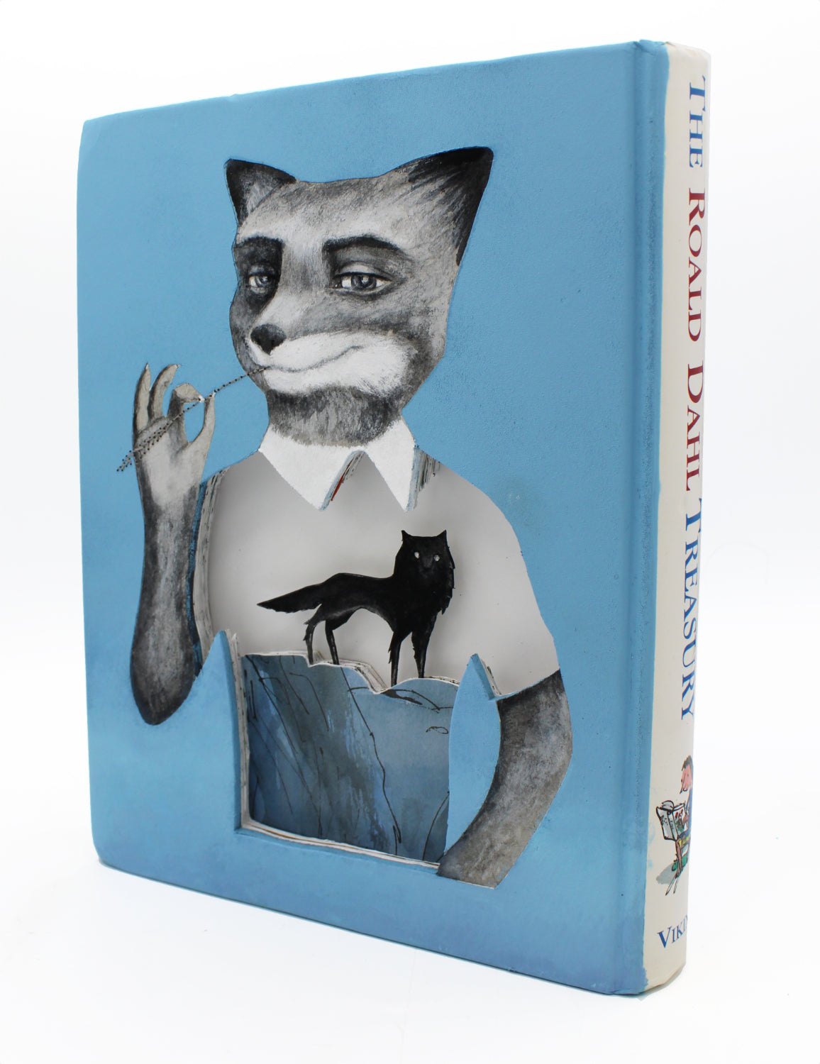 The Valerie Savarie blue book cover for The Roald Dahl Treasury features a dressed fox with a monocle, echoing Fantastic Mr. Fox. A cutout shows a fox on a rock beneath it, revealing just its feet.