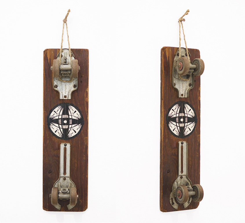 A vintage skateboard with metal wheels and wood plank features a GATS-style black and white geometric design. It is displayed by a top rope loop at Art Market San Francisco.