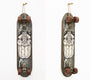 A GATS acrylic skateboard with a tribal-style symmetrical face design in black and white is mounted vertically on the wall. Featuring a vintage look and brown wheels, it was once a highlight at Art Market San Francisco.