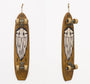 A vintage skateboard featuring GATS black acrylic design of a stylized face with closed eyes is displayed on a white background. With its carved wooden deck, the skateboard hangs upright by a rope, showcasing its trucks and wheels.