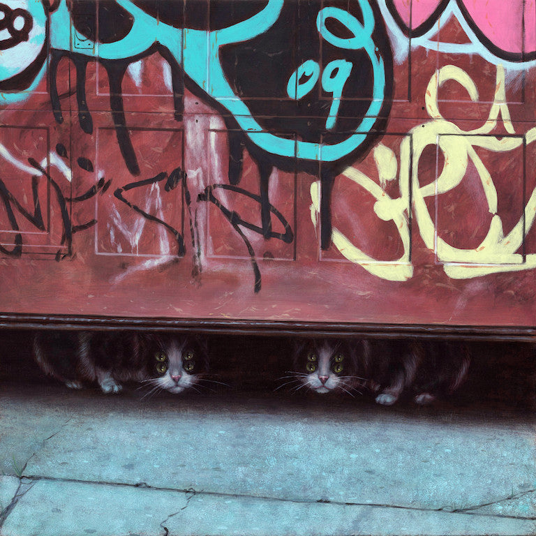 Two black and white cats peek from under a partially open garage door featuring colorful graffiti resembling an acrylic painting by Casey Weldon. The curious felines sit on the concrete, while abstract shapes evoke a vibrant canvas.