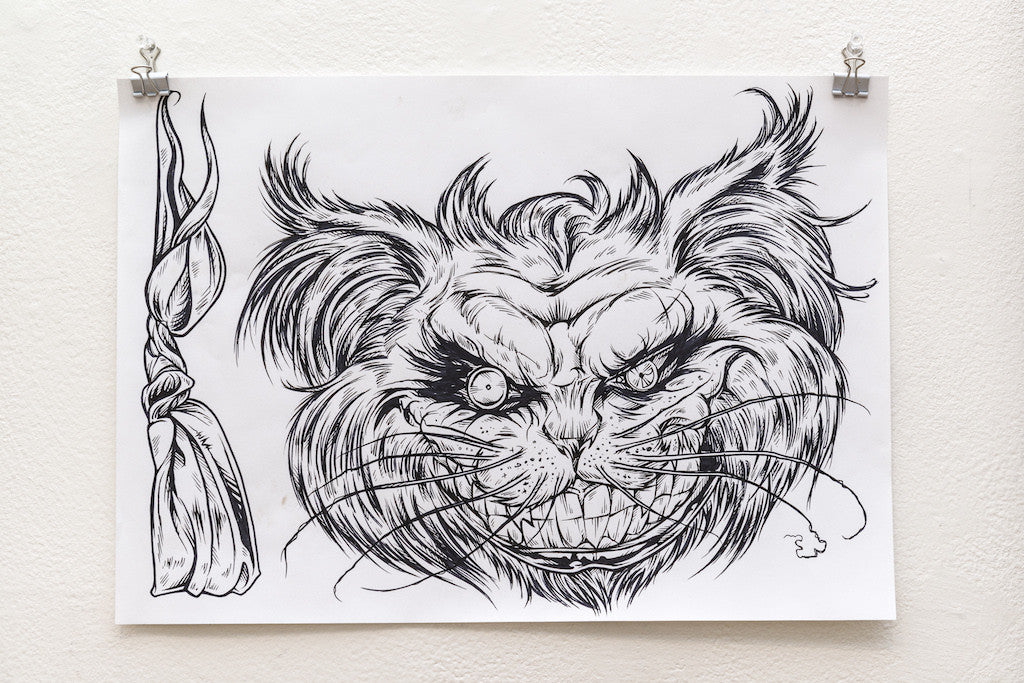 A preliminary ink sketch by Rhys Cooper, featuring a menacing feline face with exaggerated features and intense eyes, includes a twisted cord or tassel to the left. Displayed clipped on a white wall, the black and white illustration captivates with its detailed design.