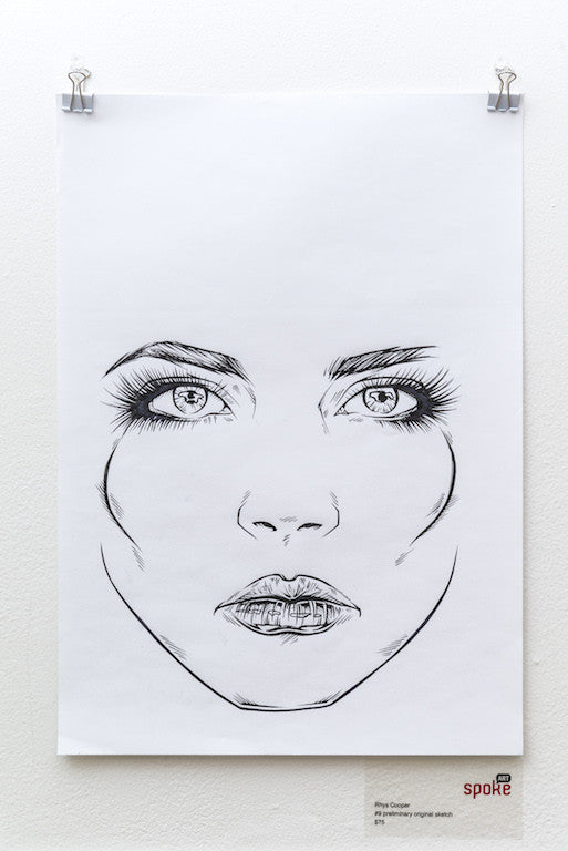 A black and white line drawing of a womans face, reminiscent of a Rhys Cooper sketch, is centered on a white sheet. The focus is on her detailed eyes and lips. This ink-on-paper artwork is clipped at the top and displayed on a pristine white wall.