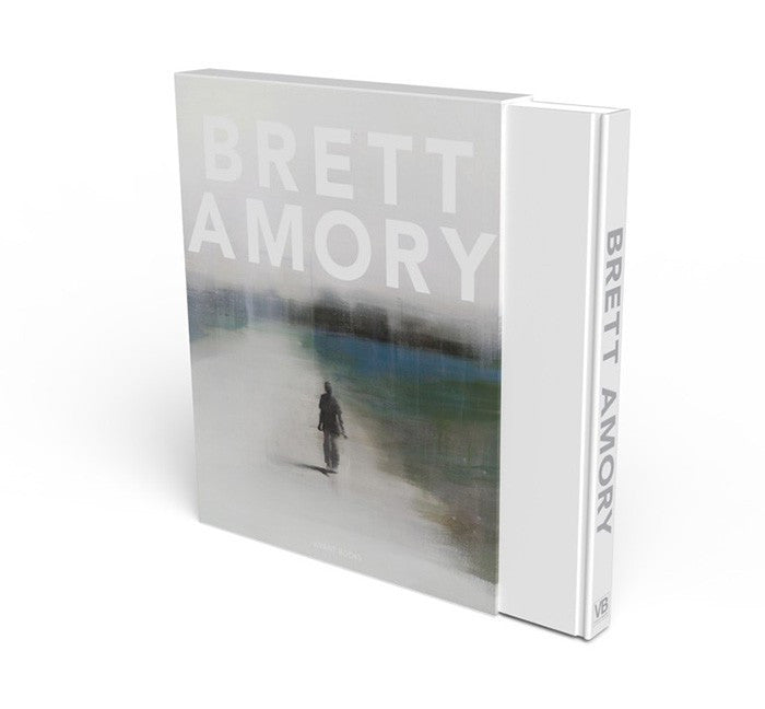The limited edition coffee table book Brett Amory features a blurred, atmospheric painting of a solitary figure walking on its cover, with the brand name Brett Amory prominently displayed on the spine.