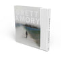 The limited edition coffee table book Brett Amory features a blurred, atmospheric painting of a solitary figure walking on its cover, with the brand name Brett Amory prominently displayed on the spine.