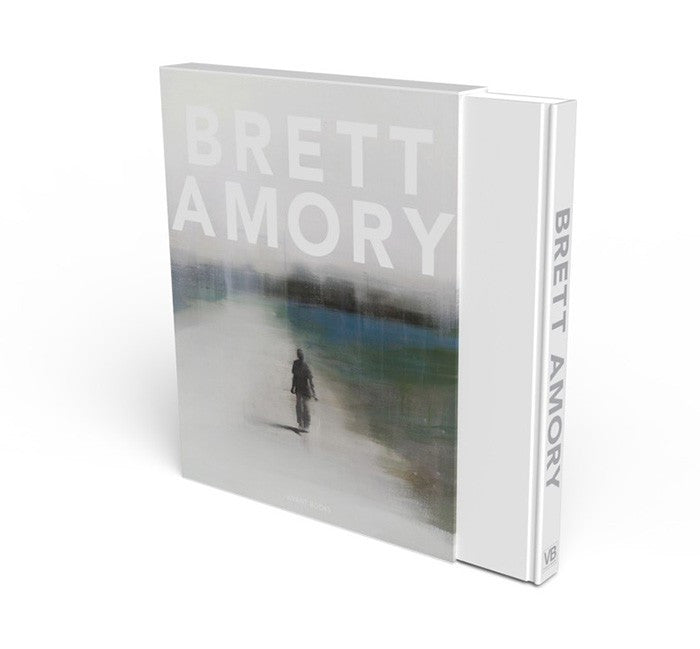 The limited edition coffee table book Brett Amory features a blurred, atmospheric painting of a solitary figure walking on its cover, with the brand name Brett Amory prominently displayed on the spine.