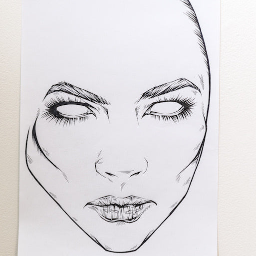 A Rhys Cooper sketch of a face features bold outlines and minimal details, with black and white ink on a white page. The eyes are blank, highlighting the strong eyebrows and lips. This preliminary piece is displayed on a wall using small hooks.