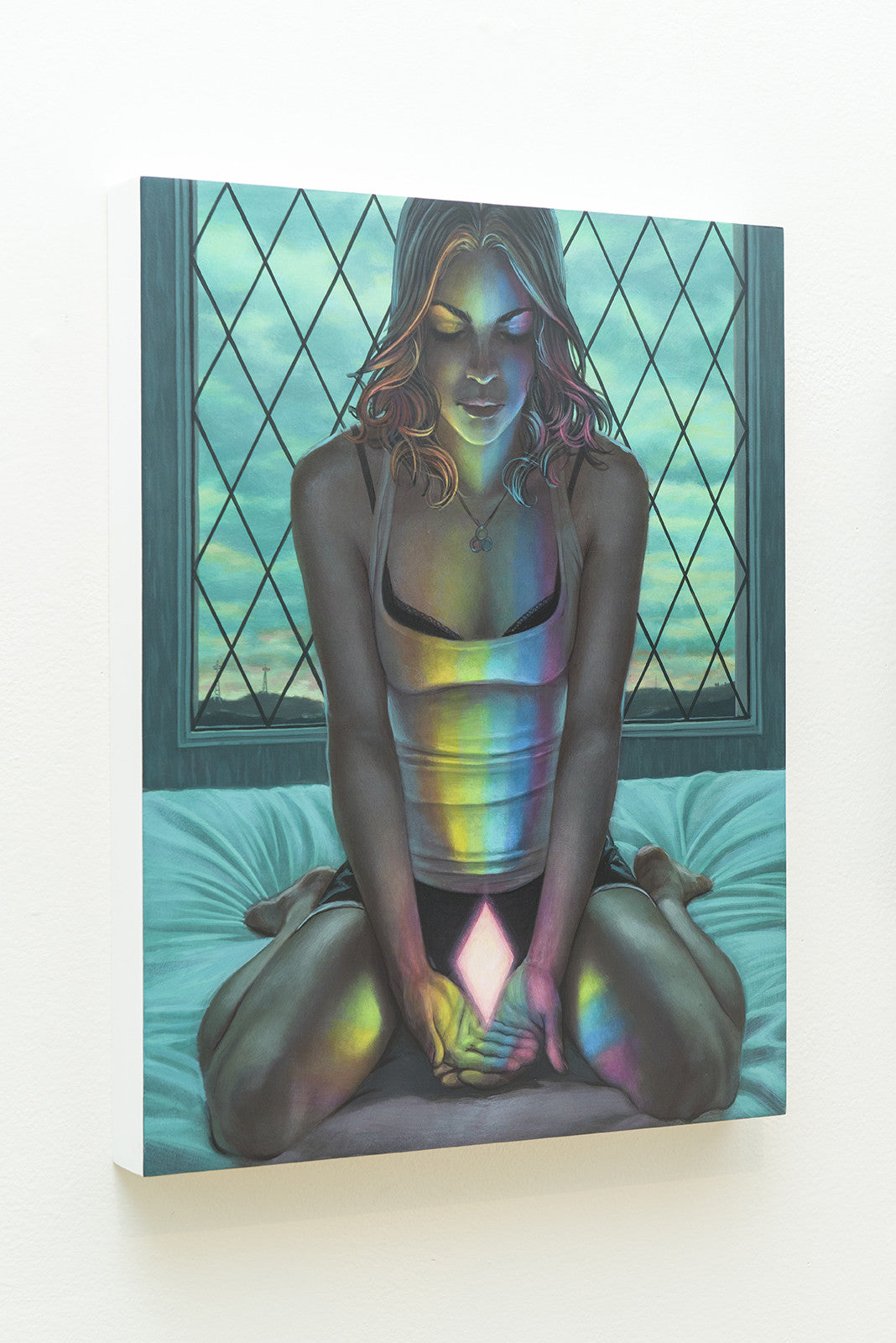 An acrylic painting depicts a woman sitting cross-legged on a bed, holding a glowing rainbow crystal that casts colorful reflections on her face and clothing. She is in front of a window featuring Casey Weldons signature geometric pattern.