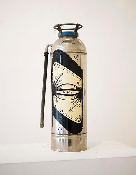 The GATS vintage silver fire extinguisher with a stylized eye design and black and white detailing stands elegantly on a clean, white surface, featuring an enamel finish that adds sophistication against the plain background.