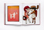 An open book features art: the left page shows a painting of a white dog with a patch on an orange background, echoing Wes Andersons style. The right page displays a cartoon boy in a raccoon hat, girl with a flower, and cat in basket—an homage to Spoke Art Gallerys Bad Dads exhibition by Matt Zoller Seitz.