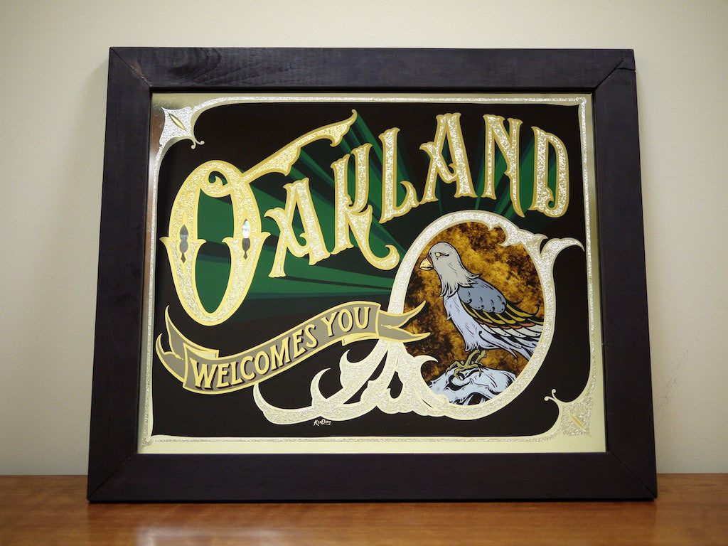 Framed artwork by Ken Davis featuring Oarland Welcomes You in decorative lettering, with a vintage style mixed media illustration of a bird and animal against a dark, muted background.