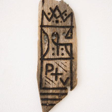 GATS presents a burnt driftwood art piece, adorned with abstract carvings of geometric shapes, lines, and symbols. Its rustic appearance contrasts beautifully against a white background.