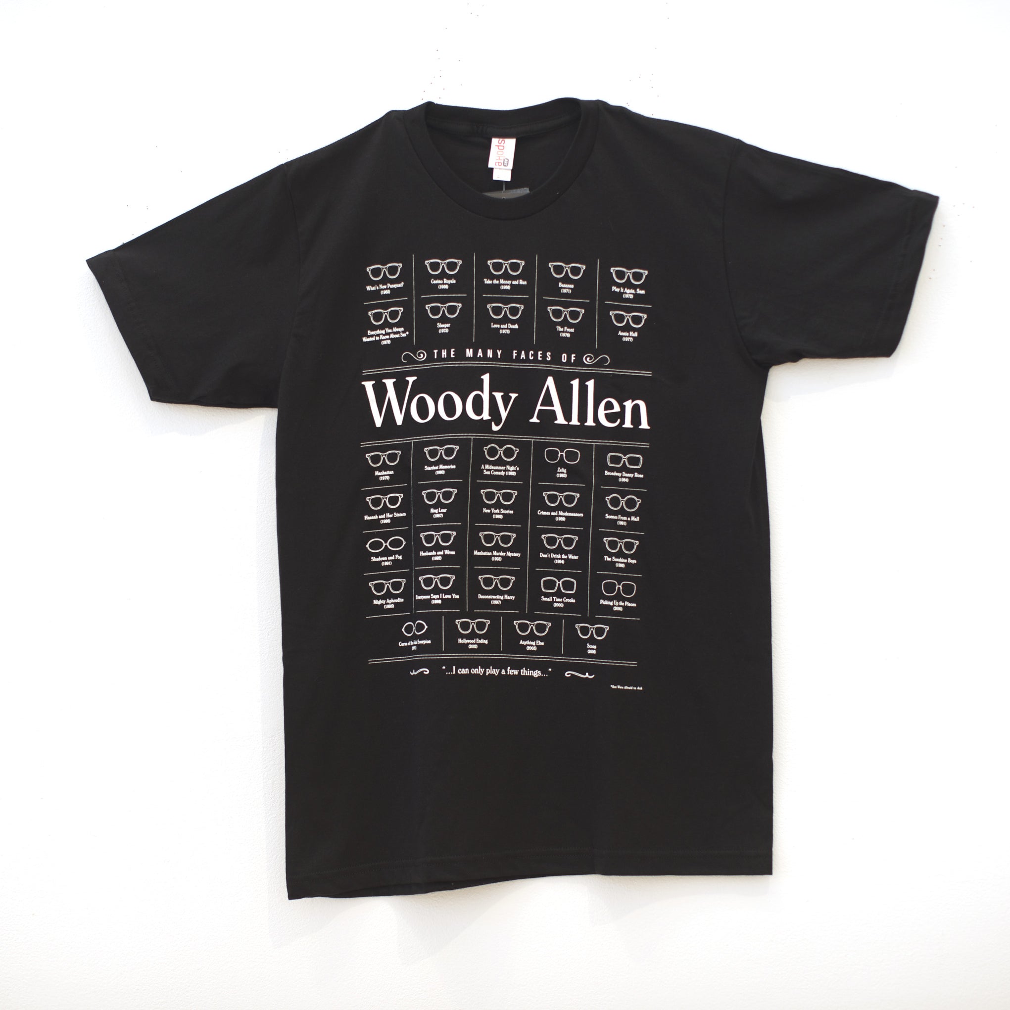 This limited edition black T-shirt by Brandon Schaefer features The Many Faces of Woody Allen, with screen-printed cartoon glasses and eyes exhibiting various expressions.