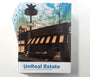 The image shows Tim Doyles hardcover book UnReal Estate: Iconic Pop Culture Locations. The cover features a comic-style illustration of The Androids Dungeon & Baseball Card Shop.