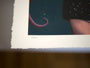 Close-up of a limited edition fine art giclee print by Ana Bagayan, featuring a textured edge and handwritten 1/20. The artwork showcases a pink tentacle against a dark background.