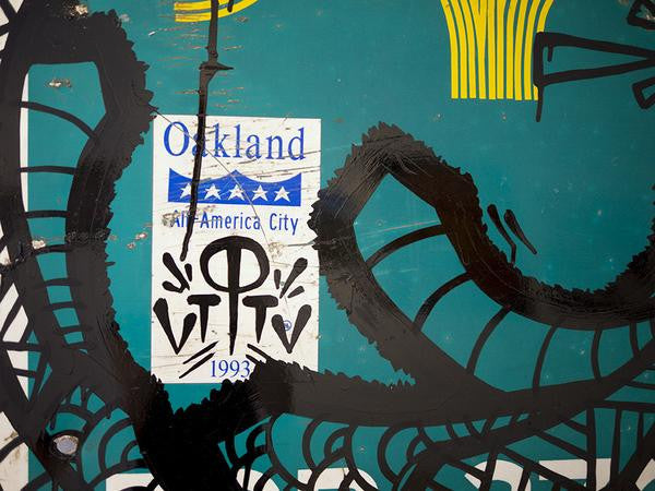A green wall showcases a sticker reading Oakland All America City 1993 with blue stars, complemented by GATS-branded black abstract patterns. Splashes of yellow complete the design, merging street art with Oaklands iconic flair.