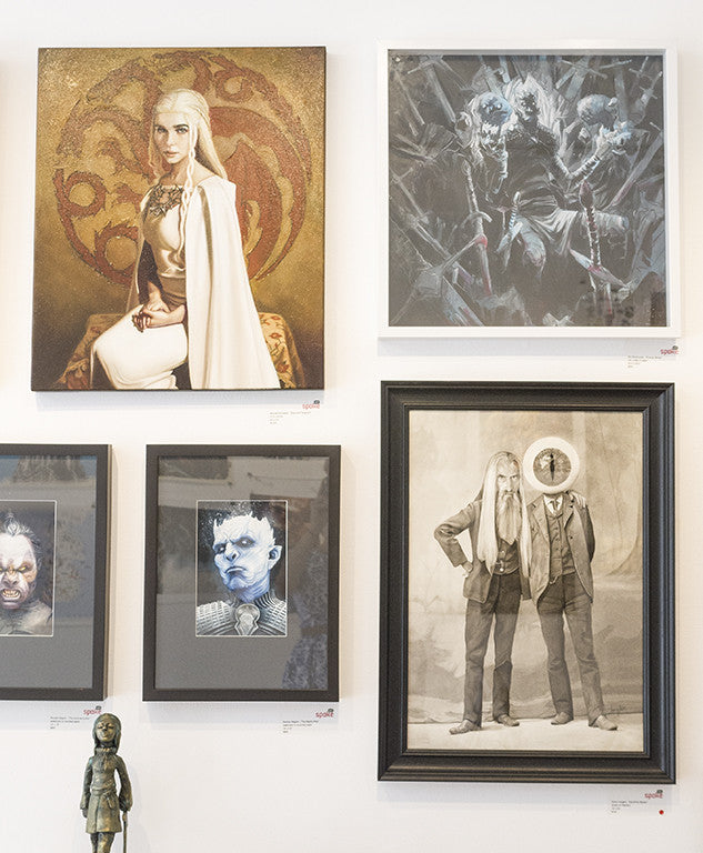 The art gallery wall features framed artworks from Michael Ramstead, showcasing enchanting fantasy portraits and monochrome sketches, including regal figures and abstract designs resembling Daenerys Targaryen. At the bottom, a small statue is artfully displayed.