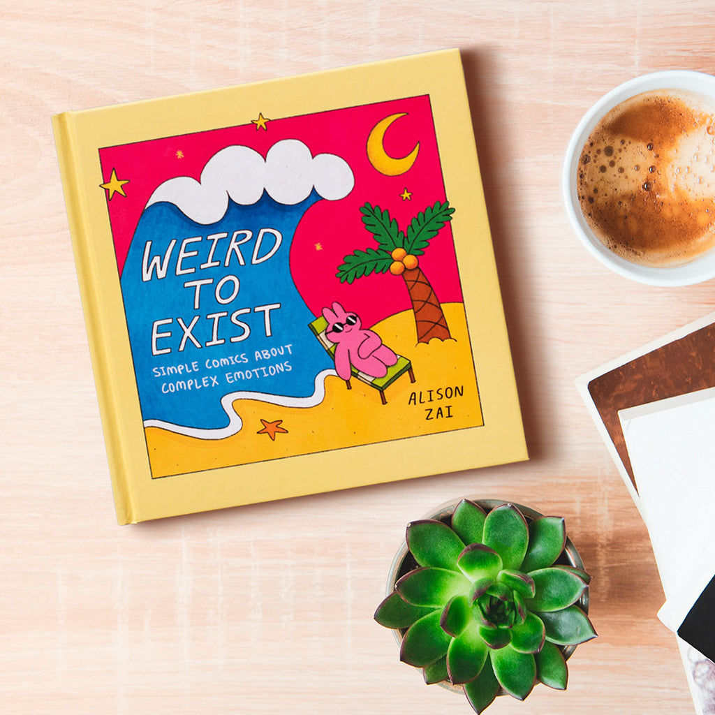 Alison Zai's Weird To Exist book on a table with succulent and coffee cup