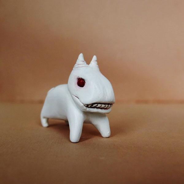 Doubleparlours hand-sculpted resin creature features a horse-like head, red eyes, and a toothy grin. Its vibrantly painted with acrylics and glossy varnish, set against a plain brown background for quirky appeal.