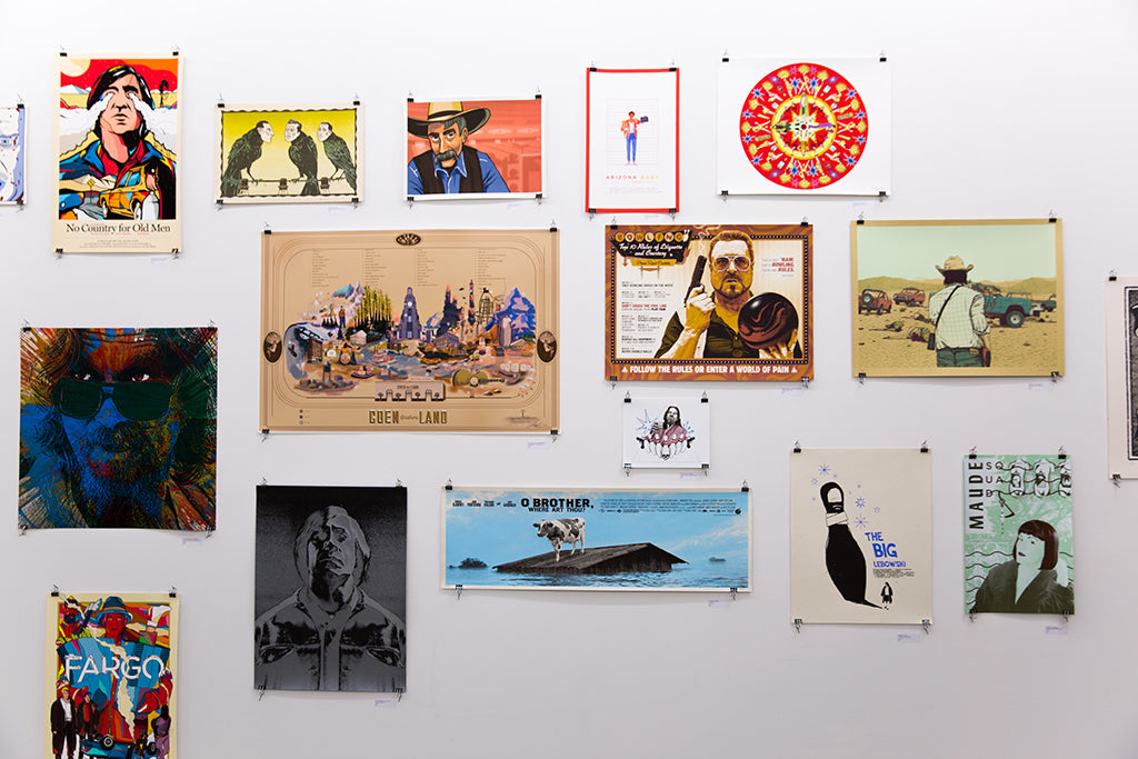 A gallery wall showcases vibrant Matt Dye posters featuring diverse designs, adorned with metallic silver accents, including portraits, abstract patterns, and movie references for an eclectic visual collection.