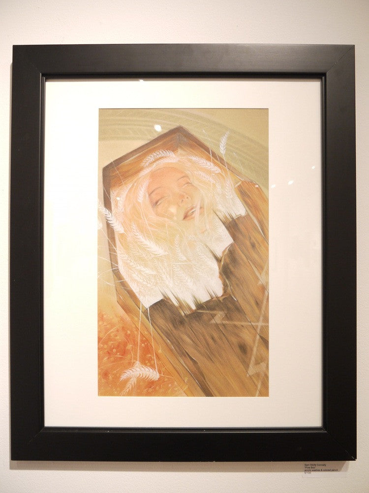 A framed artwork by Sam Wolfe Connelly depicts a woman resting gracefully in a pine box, surrounded by delicate white feathers. Soft, warm colors created with acrylic washes give the image a serene feeling.