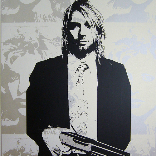 Black and white screen print artwork by Matt Dye depicts a man with shoulder-length hair in a suit, holding a gun. The background, crafted by Blunt Graffix, features abstract faces in lighter shades.