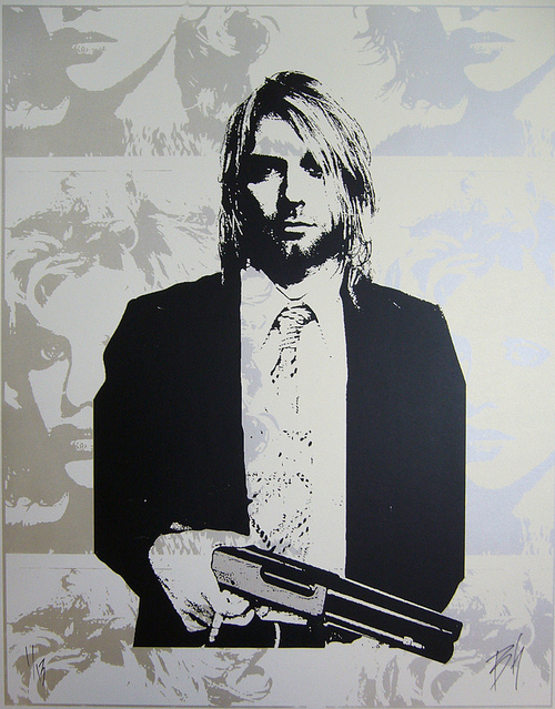 Black and white screen print artwork by Matt Dye depicts a man with shoulder-length hair in a suit, holding a gun. The background, crafted by Blunt Graffix, features abstract faces in lighter shades.