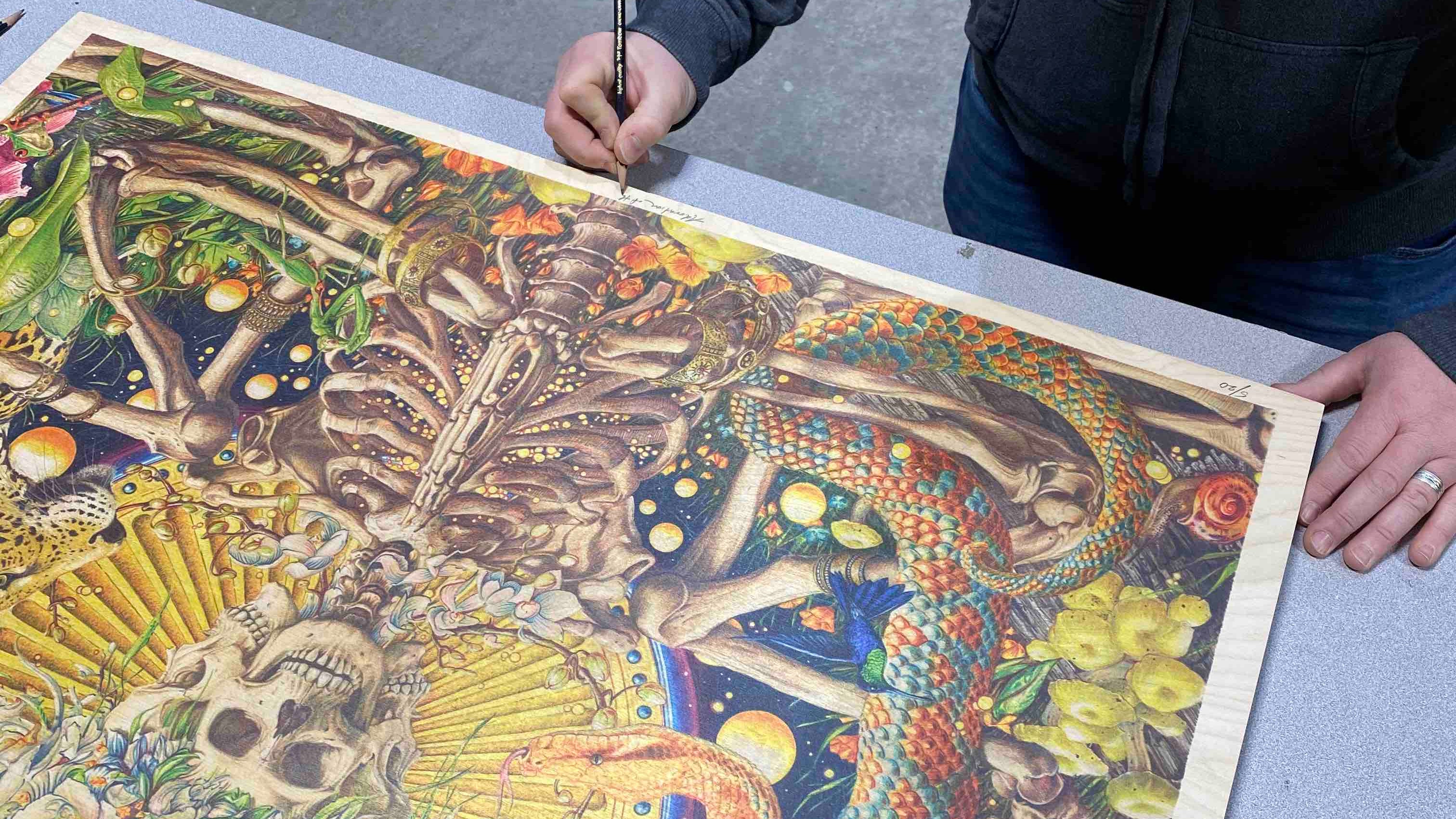 Artist AJ Masthay signing an illustration on wood panel