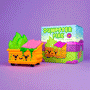 A colorful 100% Soft Dumpster Fire Vinyl Figure, shaped like a smiling dumpster with green flames and orange "Toxic Waste" details, sits by its cartoon-style box labeled Dumpster Fire on a purple background.