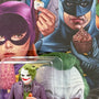 A close-up of a comic-style illustration by Alex Gross shows Batgirl holding ice cream, Batman with a cupcake, and a limited edition Joker resin figure, with part of Joker’s face in the background.