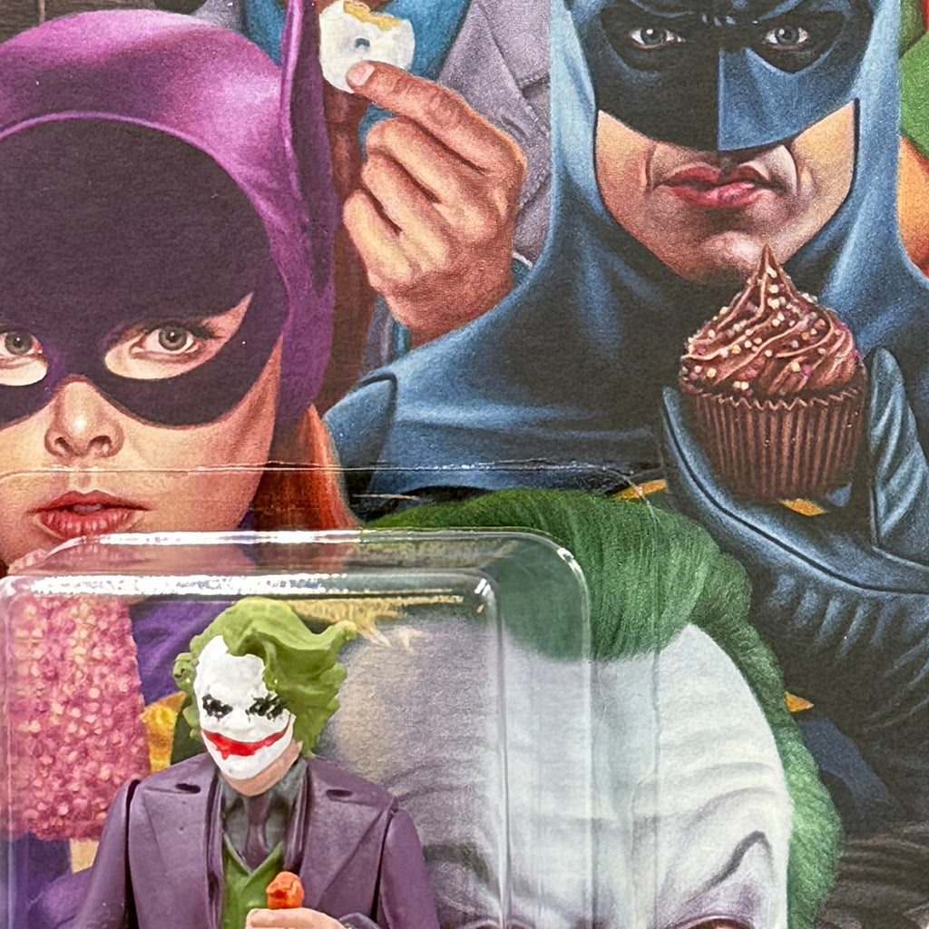 A close-up of a comic-style illustration by Alex Gross shows Batgirl holding ice cream, Batman with a cupcake, and a limited edition Joker resin figure, with part of Joker’s face in the background.