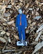 Cardboard cutout of a person in blue jacket and orange shirt on wood chips
