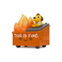 A 100% Soft Dumpster Fire vinyl figure depicts a toy dog wearing a hat sitting on top of an orange dumpster with flames inside. The dumpster has a smiley face and the words “THIS IS FINE.” printed on the side, perfectly capturing the iconic This is Fine meme in this KC Green collaboration.