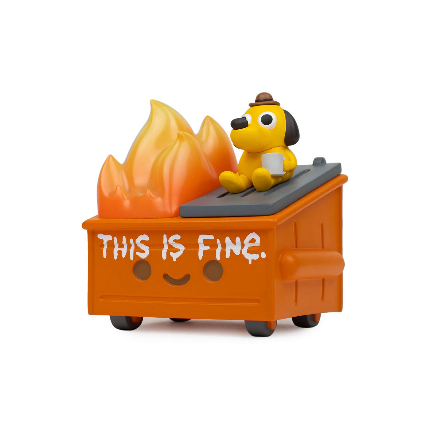 A 100% Soft Dumpster Fire vinyl figure depicts a toy dog wearing a hat sitting on top of an orange dumpster with flames inside. The dumpster has a smiley face and the words “THIS IS FINE.” printed on the side, perfectly capturing the iconic This is Fine meme in this KC Green collaboration.
