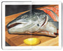 open faced Moleskine notebook with a still life painting of a chopped salmon head on a wooden cutting board, with a lemon wedge beside it by artist David Rice