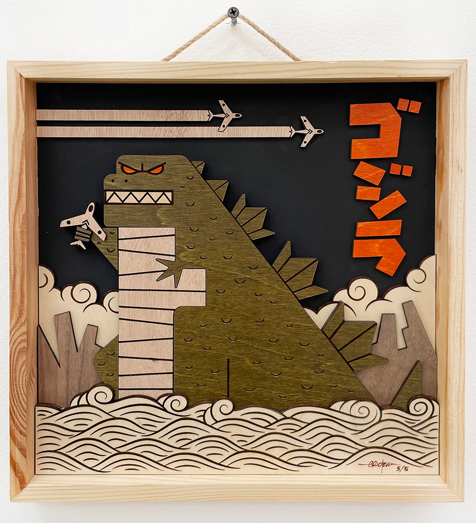 Image created from wood of Godzilla holding an airplane in the water with a black background and two airplanes flying above him