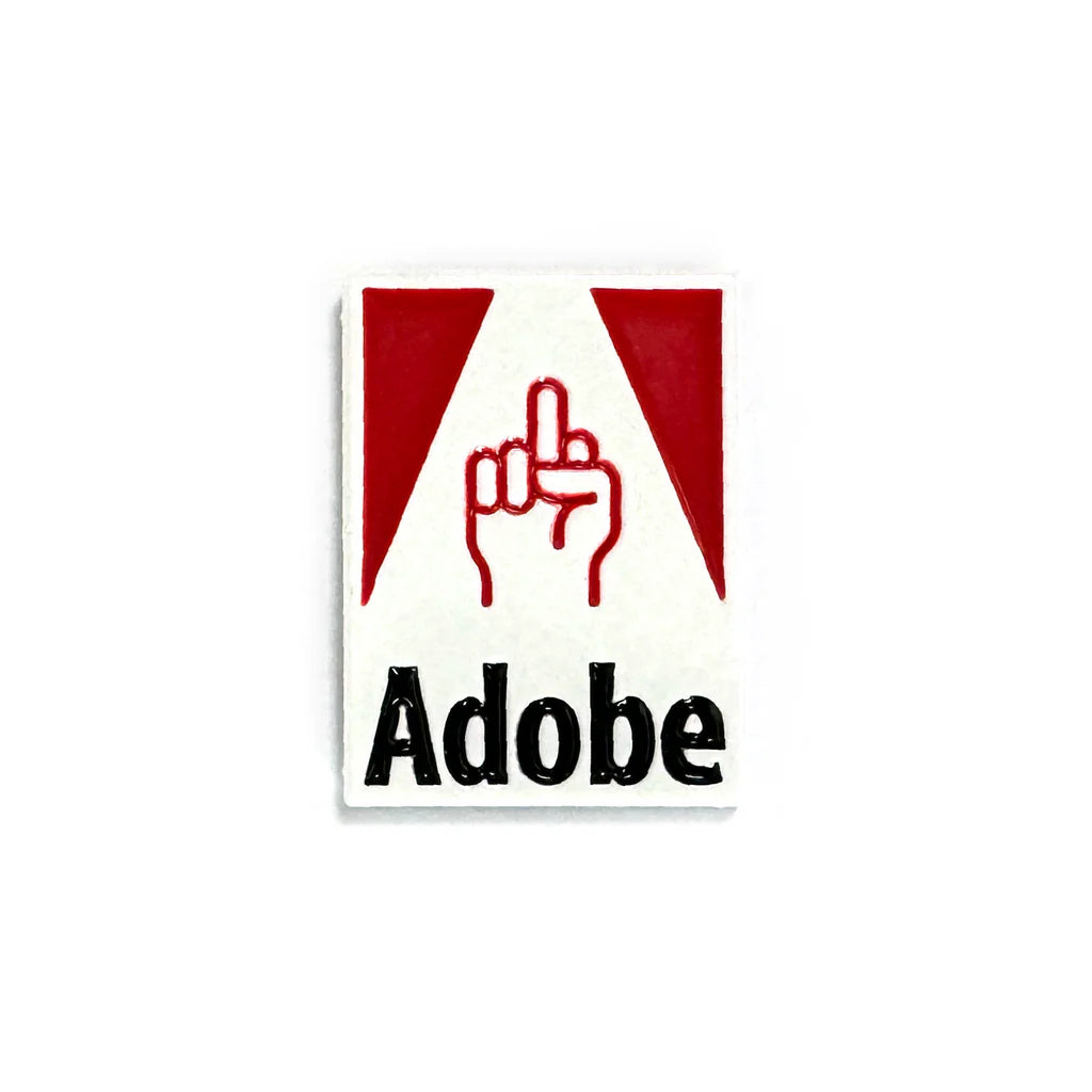 A limited edition enamel pin parodying Adobe’s logo, with a hand giving the middle finger between red triangles above bold “Adobe” text. Created by Spoke Art, this unique lapel pin stands out on any jacket or bag.