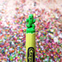 Green cactus-shaped marker cap on a yellow marker against a colorful blurred background