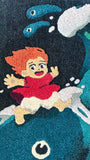 A vibrant hand-dyed wool yarn art rug by Spoke Art shows a red-haired animated girl riding a blue fish-like creature, with water splashes and two small sea creatures, commemorating Spoke Art’s 15th Anniversary.