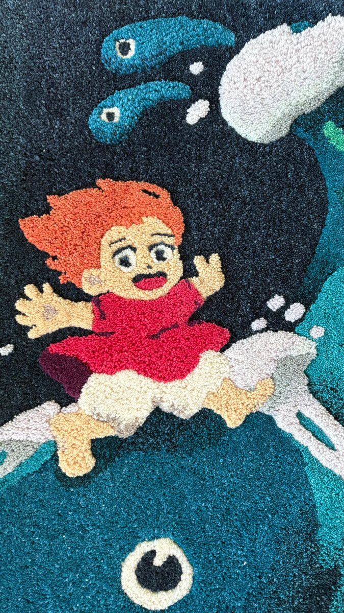 A vibrant hand-dyed wool yarn art rug by Spoke Art shows a red-haired animated girl riding a blue fish-like creature, with water splashes and two small sea creatures, commemorating Spoke Art’s 15th Anniversary.