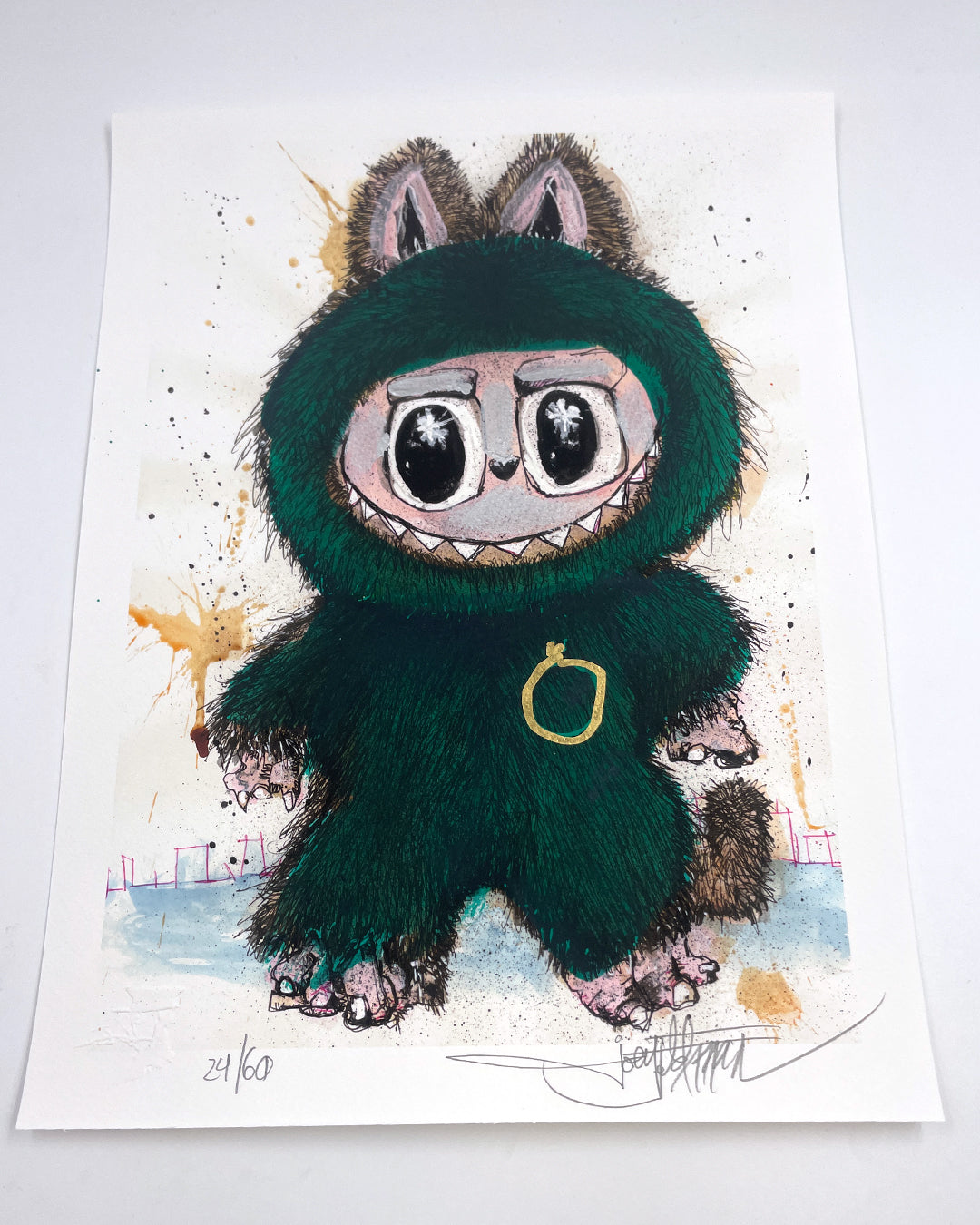 A whimsical archival print by Joey Feldman featuring a wide-eyed creature in a fuzzy green suit with pointy ears, claws, and a gold ring on its chest. Numbered 24/60 and signed at the bottom.